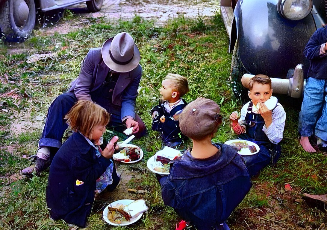 The same 1940 picnic colorized: green grass, denim overalls and warm afternoon light