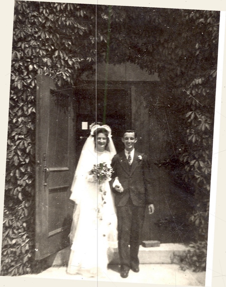 A skewed, scratched black-and-white 1945 wedding photograph of a couple in a doorway